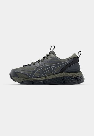 Scarpa sportiva grigia scura con tomaia in mesh testurizzato, suola in gomma, dettagli riflettenti e soletta ammortizzata. Presenta un design con lacci.