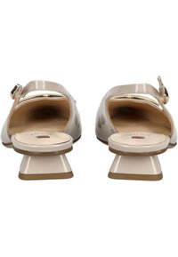 Zapatos de charol beige con punta redondeada y un tacón bajo cuadrado. El diseño cuenta con una pequeña correa para el tobillo con una hebilla metálica.