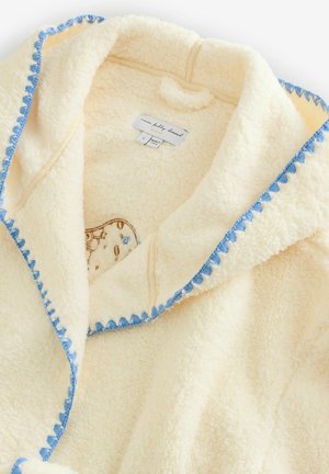 Krémově zbarvená fleecová bunda s modrým lemováním, vybavená kapucí, měkkou texturou a vzorovanou vnitřní podšívkou. Označená informací o velikosti.