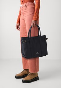 Navyblaue Leder-Tote mit einem strukturierten Design, doppelten Obergriffen, goldfarbener Hardware und einem seitlichen Schnallendetail.