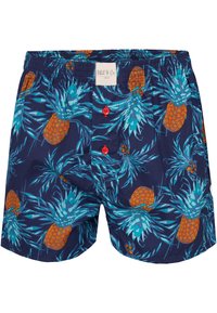 Námořnické modré plavky s vzorem ananasů a palmových listů, s červenými knoflíky a elastickým pasem pro pohodlí.