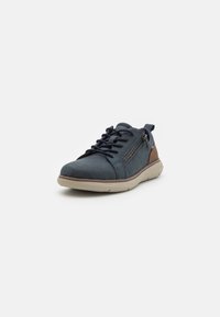 Zapatillas de ante azul marino con cierre de cremallera, punta redonda y suela de goma beige. Con detalles de cuero marrón en el talón y el costado.