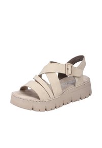 Sandale en cuir beige avec des brides entrecroisées, boucle ajustable et semelle épaisse et striée. Intérieur doux avec une semelle légèrement texturée.