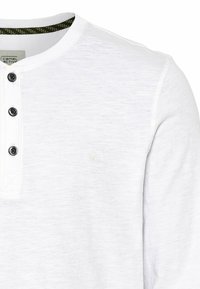 Weißes Henley-Shirt mit strukturiertem Stoff, ausgestattet mit einem Rundhalsausschnitt, drei schwarzen Knöpfen und einem dezenten Logo auf der Brust.