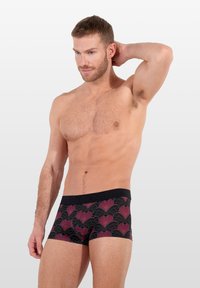 Zwarte boxers met een herhalend, gestileerd roze en zwart patroon, voorzien van een merkband in het zwart. Gladde stof en een aansluitend ontwerp.