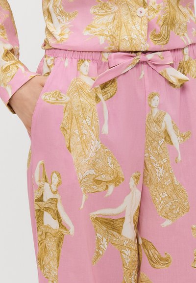 Calças de tecido rosa com um padrão floral e de figuras em dourado, apresentando uma cintura elástica e um detalhe de laço na frente.