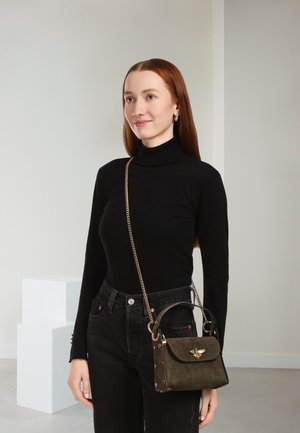 Grüne Wildlederhandtasche mit goldfarbenen Beschlägen, verziert mit einem Bienenemblem, abnehmbarem Kettenriemen und strukturierter Form. Wird quer über den Körper getragen.