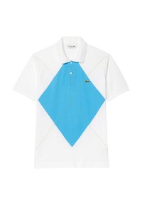 Camisa polo blanca con una gran forma de diamante azul en el frente, acentuada con costuras verdes. Logo de Lacoste en el lado izquierdo.