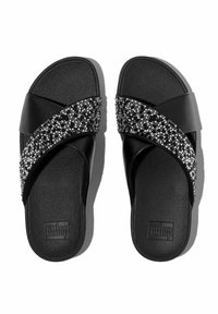 Ciabatte nere con fasce incrociate decorate con strass neri e bianchi, soletta testurizzata e suole piatte. Logo "fitflop" visibile.