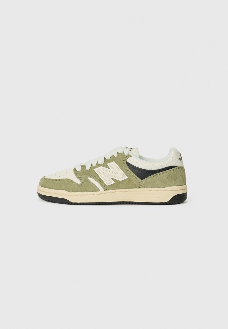 Baskets basses avec suède vert et panneaux en cuir blanc, bout perforé, lacets blancs, semelle intermédiaire beige et semelle extérieure noire, vue latérale.