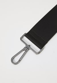Sangle en nylon noir avec une finition texturée, dotée d'un clip en métal et d'un matériel d'ajustement rectangulaire. Design simple et durable pour une fixation.