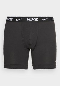 Sorte bomuldsboxershorts med et hvidt Nike-logo på linningen. Har en tætsiddende pasform, korte ben og en glat tekstur.