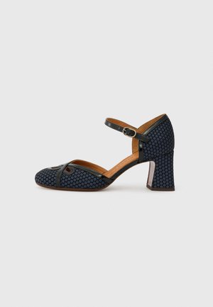 Blue patterned high-heeled shoe with a textured surface, open toe, and ankle strap. Features a rounded toe shape and a block heel.