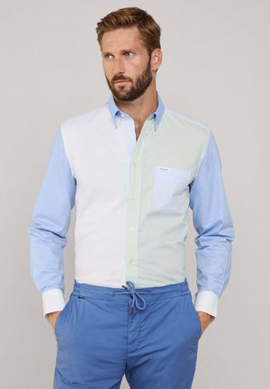 Camicia con bottoni caratterizzata da pannelli blu chiaro, verde pallido e bianco, con una tasca a righe. Include polsini bianchi e un design di colletto classico.