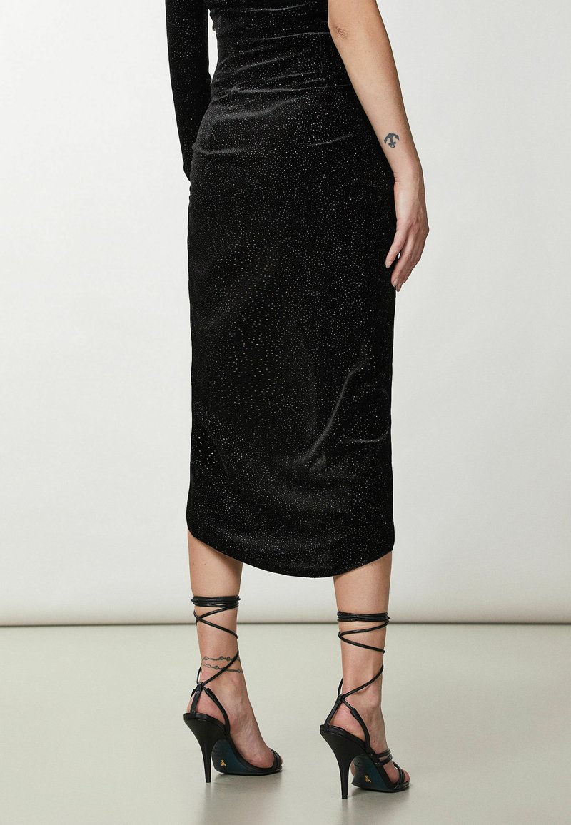 Czarna, dopasowana sukienka o welurowej fakturze i błyszczących akcentach. Posiada długość midi, boczne rozcięcie oraz strappy wysokie sandały.