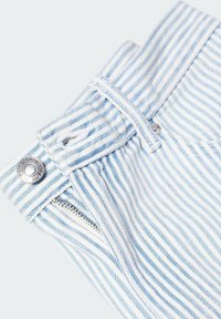 Pruhované džíny v kombinaci světle modré a bílé barvy, se zipem, knoflíkovým zapínáním a texturovanou tkaninou s viditelnými švy.