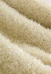 Flauschiger Stoff in Beige mit glänzenden goldenen Fäden. Weiche Textur, geschichtetes Design mit unterschiedlich langen Fasern. Geeignet für gemütliche Anwendungen.