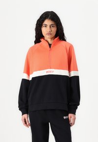 Pullover Roxy in corallo brillante e nero, con zip, striscia bianca, vestibilità ampia e polsini a costine; realizzato in tessuto morbido.