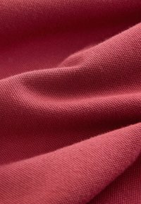 Material carmin cu un model texturat tricotat, prezentând o suprafață moale, netedă și variații subtile de culoare.