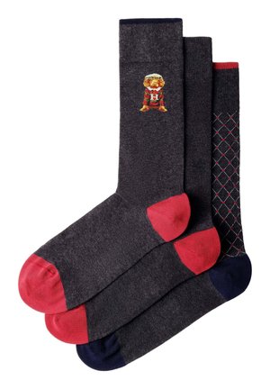 Three pairs of dark gray socks with colored toes and heels; one has a dog in a striped sweater, another is plain, the third has a diamond pattern.