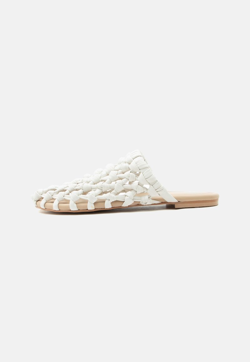 Sandale blanche tissée à enfiler avec semelle plate couleur beige et tige en tissu tressé, conçue pour un usage décontracté.