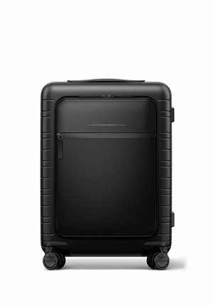 Black hard-shell suitcase with front zippered pocket and four wheels, standing upright on a white background.