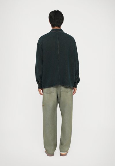 Mørk denim overskjorte med lange ermer, kragehals og drop shoulders. Kombinert med vide, falmede olivengrønne jeans.