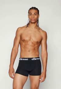 Black boxer briefs with a white "ellesse" waistband. Smooth fabric and fitted design. Worn by a person with a toned physique.