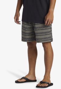 Mönstrade badshorts med ett design av marinblå och krämfärgade diamanter, tillverkade av lättviktig tyg. Bärs med svarta flip-flops, ihop med en mörk topp.
