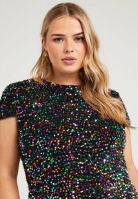 Top nero coperto di paillettes multicolori; maniche corte; texture morbida; scollatura rotonda; finitura lucida con accenti vivaci.