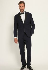 Marineblauwe tuxedo met satijnen zwarte pieklapels, een witte overhemd en een zwarte vlinderdas. Glanzende zwarte schoenen maken de formele uitstraling compleet.