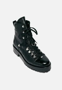 Botín negro de cuero hasta el tobillo con un patrón de croc texturizado, herrajes plateados y cordones planos; cuenta con una suela gruesa y robusta para un buen agarre y durabilidad.