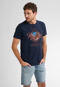 Tmavě modré bavlněné tričko s kulatým výstřihem, krátkými rukávy a vintage stylovým grafickým potiskem v korálové a modré barvě s nápisem "Miami U.S.A."