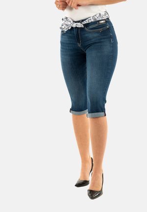 Dunkelblaue Denim-Capri-Jeans mit umgeschlagenen Säumen. Verfügt über einen weißen gemusterten Taillengürtel und einen metallischen Reißverschlusstascheneinsatz.