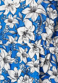 Un tissu bleu avec un motif floral composé de lys blancs et de contours noirs. La texture semble lisse avec des sections froncées.