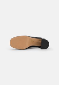 Black leather shoe with a square toe and a low, rounded heel. The sole is beige, featuring minimal texture. Marked with size 37.