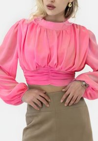 Fuchsia cropped blouse with gathered, voluminous sleeves; soft, sheer fabric; paired with a tan high-waisted skirt.