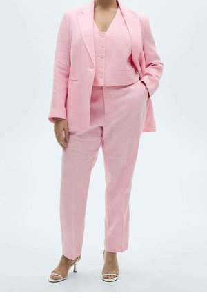 Traje de lino rosa que incluye un blazer entallado, un chaleco corto con botones y pantalones de pierna recta, complementado con tacones neutros de tiras.