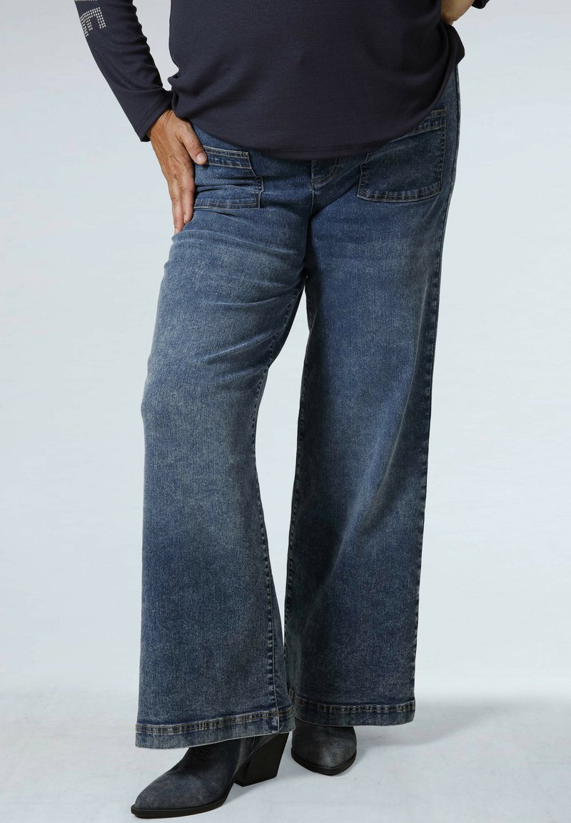 Wijdvallende denim jeans in medium blauw met een vervaagde wassing. Voorzien van voor- en achterzakken. Draag met donkere hakken.