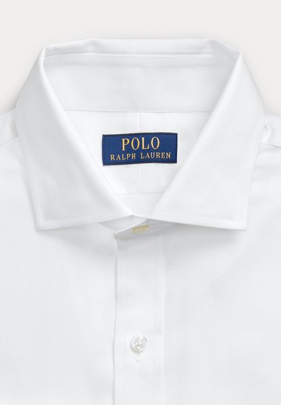 Hvid skjortekrave med en blå label med teksten "Polo Ralph Lauren" i gult, hvor den øverste knap er knappet.