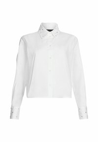 Camicia bianca cropped con maniche lunghe, chiusura con bottoni e un colletto accentuato da borchie metalliche sui polsini. Tessuto dalla superficie liscia.