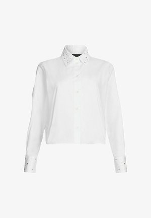 Camicia bianca cropped con maniche lunghe, chiusura con bottoni e un colletto accentuato da borchie metalliche sui polsini. Tessuto dalla superficie liscia.