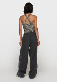Top in stampa leopardata con spalline incrociate, abbinato a pantaloni a gamba larga grigio scuro con pannelli laterali in satin.