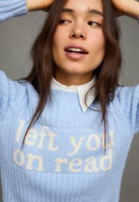 Svetlomodrý pletený sveter s okrúhlym výstrihom a rebrovanou textúrou. Na prednej strane je nápis „left you on read“ v jemných krémových písmenách.
