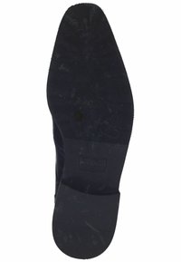 Suola di scarpa in gomma nera con motivi superficiali testurizzati, leggeri segni di usura e un logo di marca visibile nella sezione del tallone.
