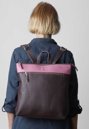 Brauner Leder-Rucksack mit einem oberen Abschnitt in Pink, ausgestattet mit verstellbaren Riemen und einer vorderen Reißverschlusstasche. Glatte Textur und modernes Design.