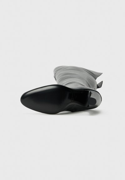 Black high-heeled boot with a pointed toe and soft gray fabric upper, featuring draped texture and a smooth sole.