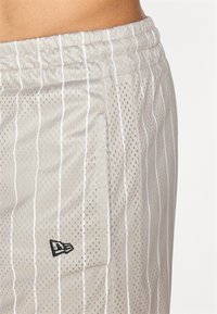 Light gray mesh shorts featuring vertical white stripes, elastic waistband, and small black logo on the side. Textured surface with perforations.