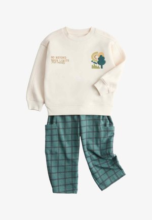Sweatshirt crème avec texte "Go Beyond Your Limits" et un graphique d'arbre. Pantalon à carreaux verts avec poches et taille élastique. Tissu doux.