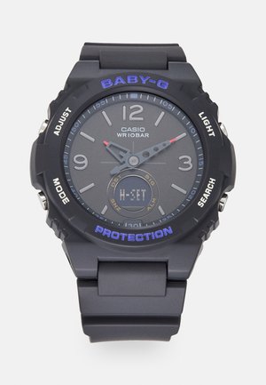 Montre Casio Baby-G noire avec un cadran rond, un cadran gris, des chiffres audacieux et des accents violets. Comprend des fonctions chronomètre et lumière. Bracelet en caoutchouc.